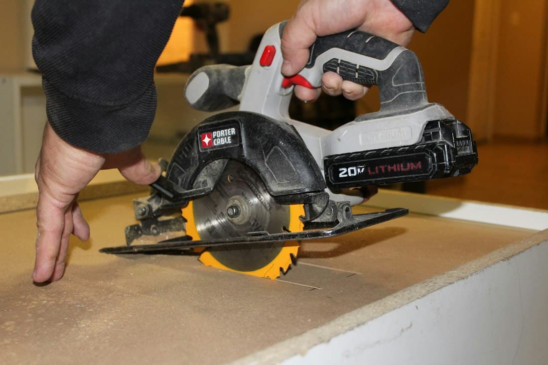 Hands cutting a board with a circular saw